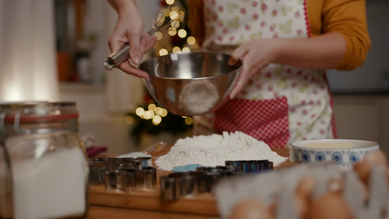 烘烤圣诞饼干时，一名妇女将搅打好的鸡蛋倒入面粉中视频素材