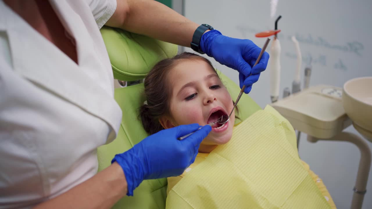 关怀女牙医使用牙科探针和角度镜，而做蛀牙状态的年轻病人视频下载