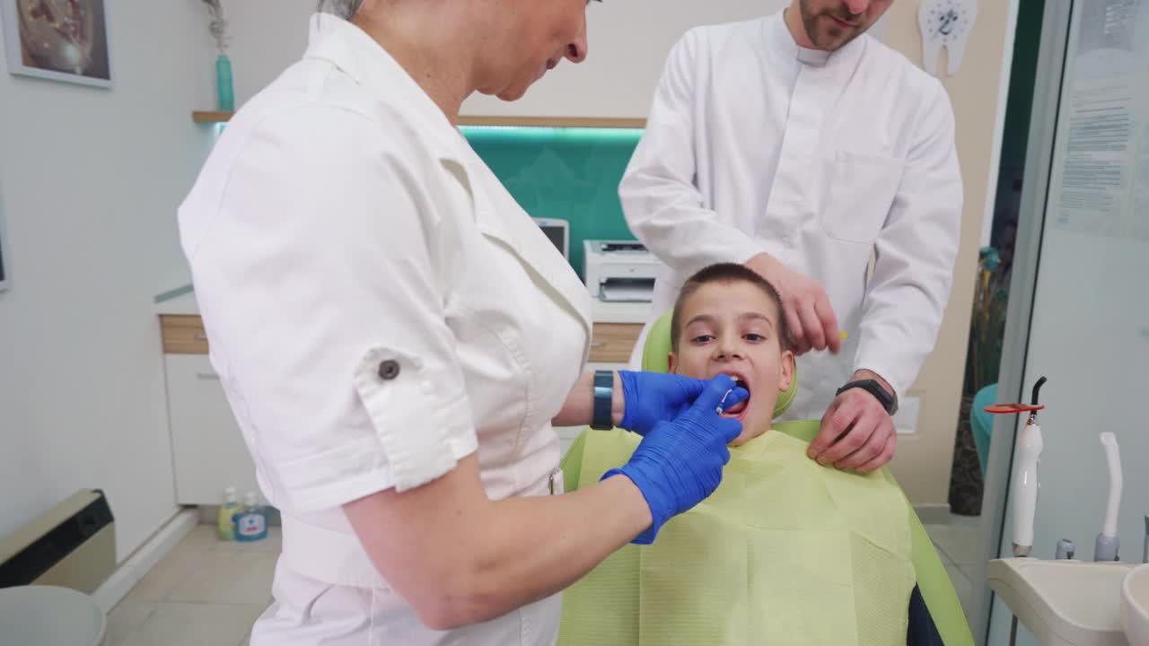 吓坏了的男孩捂着嘴，在牙科医生的椅子上拒绝合作拔牙视频素材