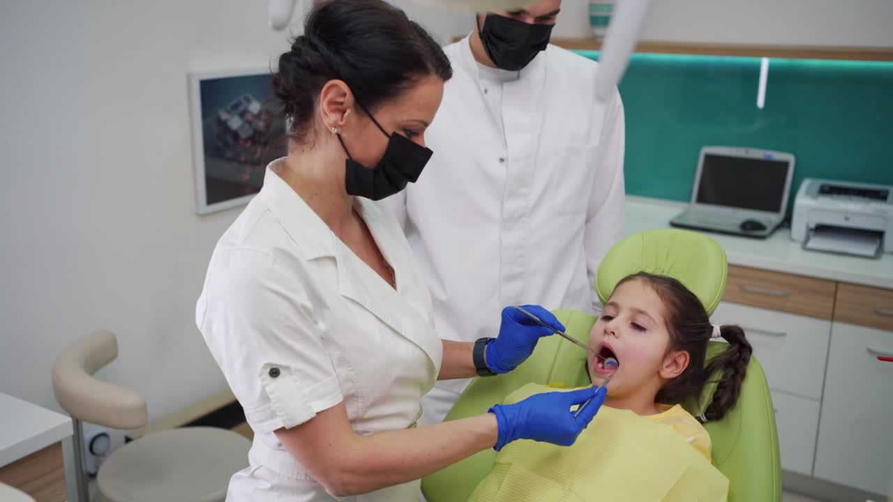 专业的女牙医使用牙科探针和角度镜，而做的牙齿状态的女性儿童视频素材