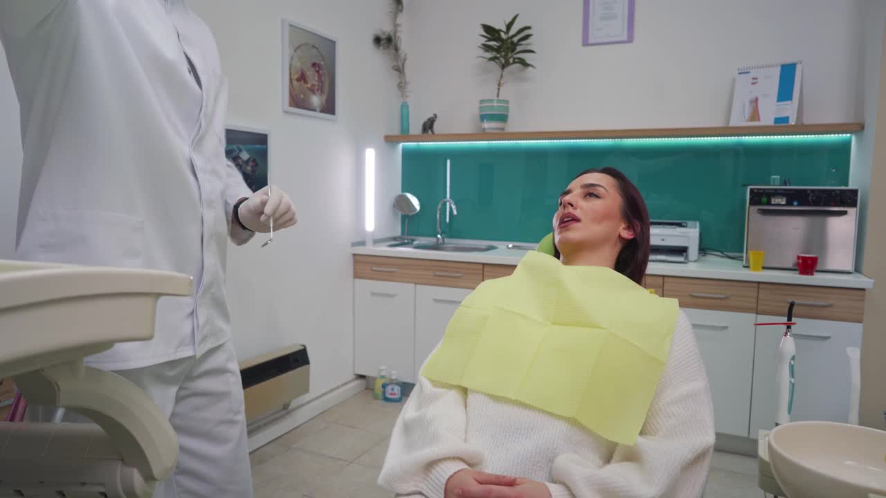 牙科医生检查口腔健康时，一位女士解释自己牙痛的症状视频素材