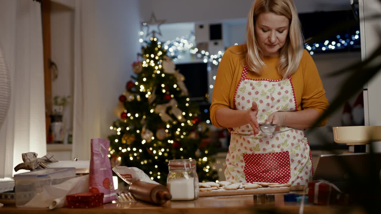 在厨房里，女人在刚烤好的饼干上洒上糖粉视频素材
