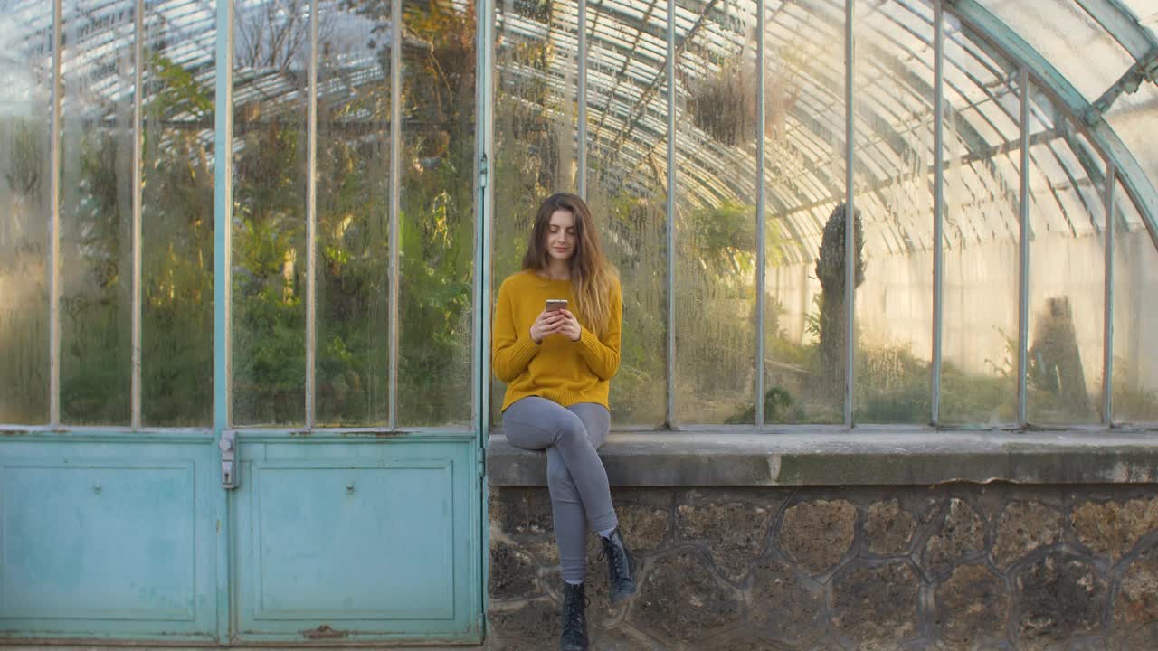 在温室外面用智能手机的女人视频素材