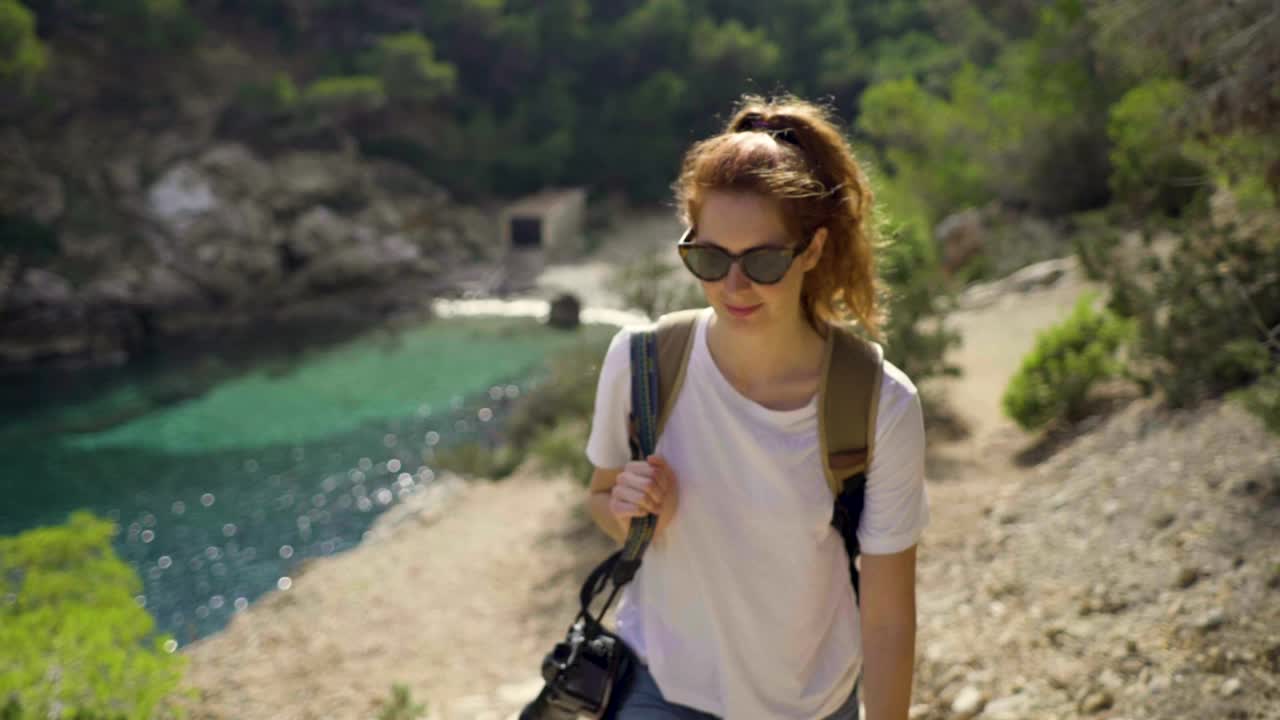 一名红发女子在伊比沙岛海岸行走的慢镜头视频素材