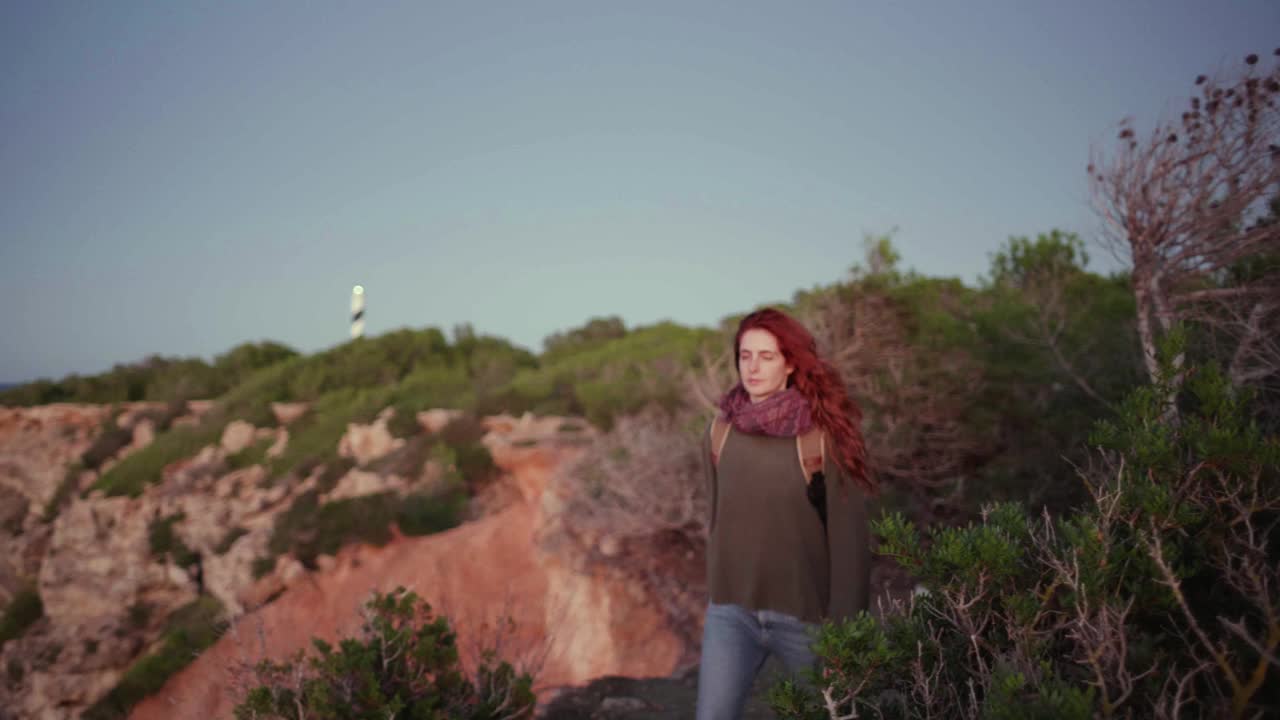 在伊比沙岛的悬崖边，一个微笑的红发女人视频素材