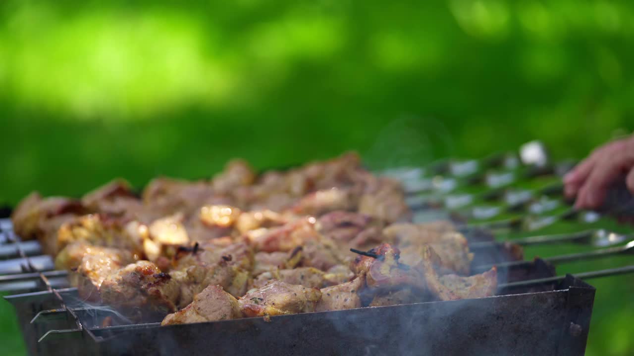 在木炭上烤肉。在木炭烤架上串上烤肉的烹饪过程。准备烧烤的男人和美味的烤肉。视频素材