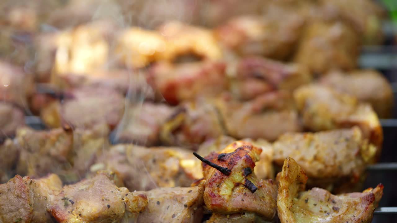 烧烤的烟雾。肉串在烤架上烤。自然界中的猪肉。在炭火上烹饪美味的烤肉串。特写镜头。视频素材