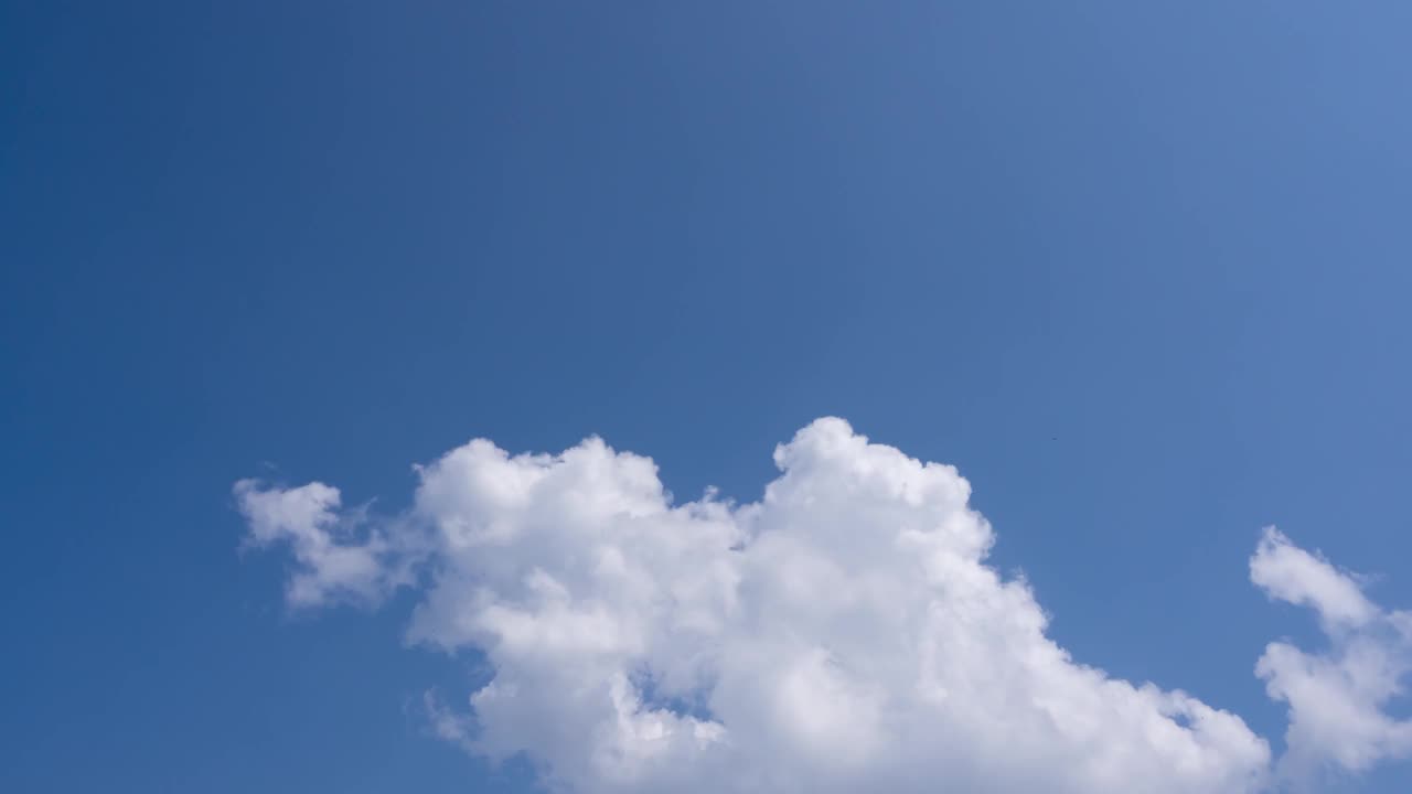 慢镜头蓝色的天空，蓬松的积云，棉花糖云在屏幕的角落。晴天的云。阳光透过云在蔚蓝的天空照耀。鸟瞰图skycaps背景拷贝空间。视频素材