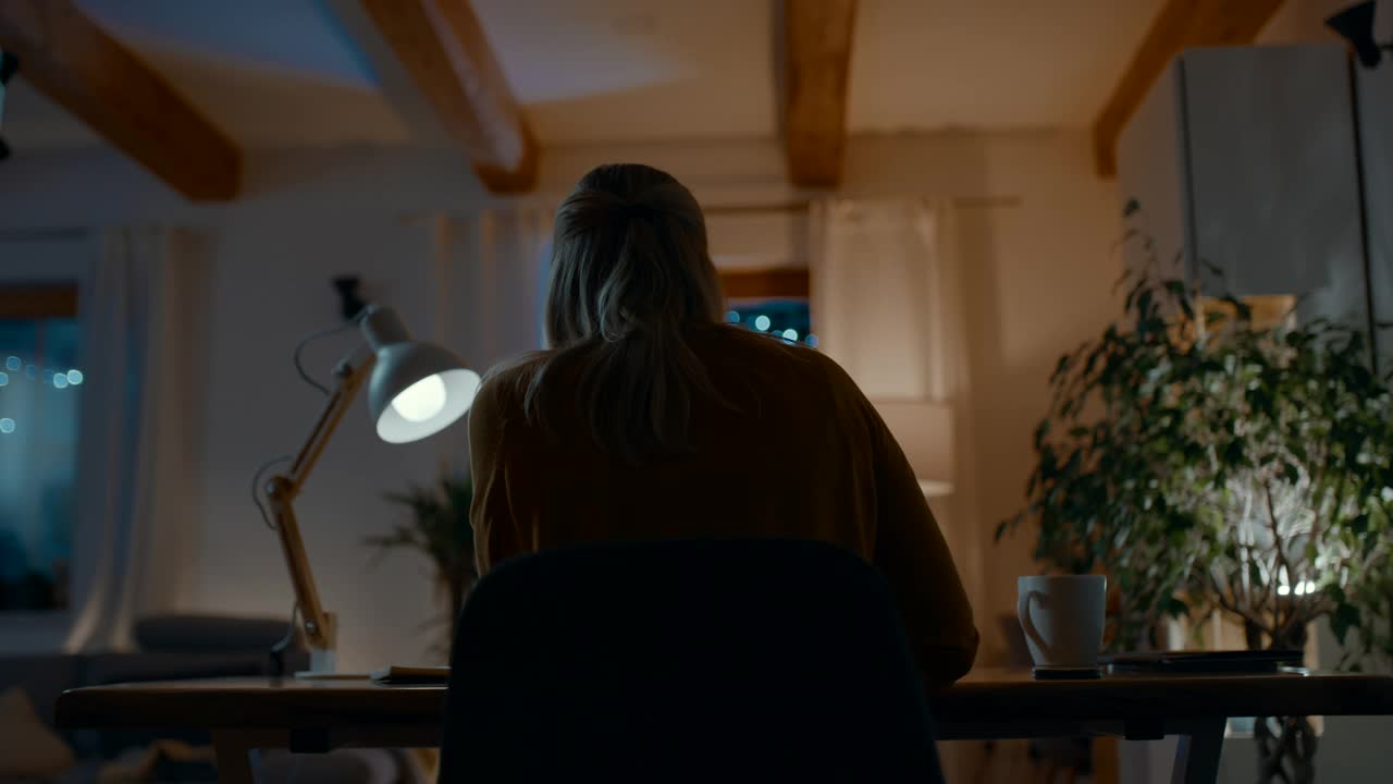 一个面目全非的女人在晚上用笔记本电脑工作视频素材