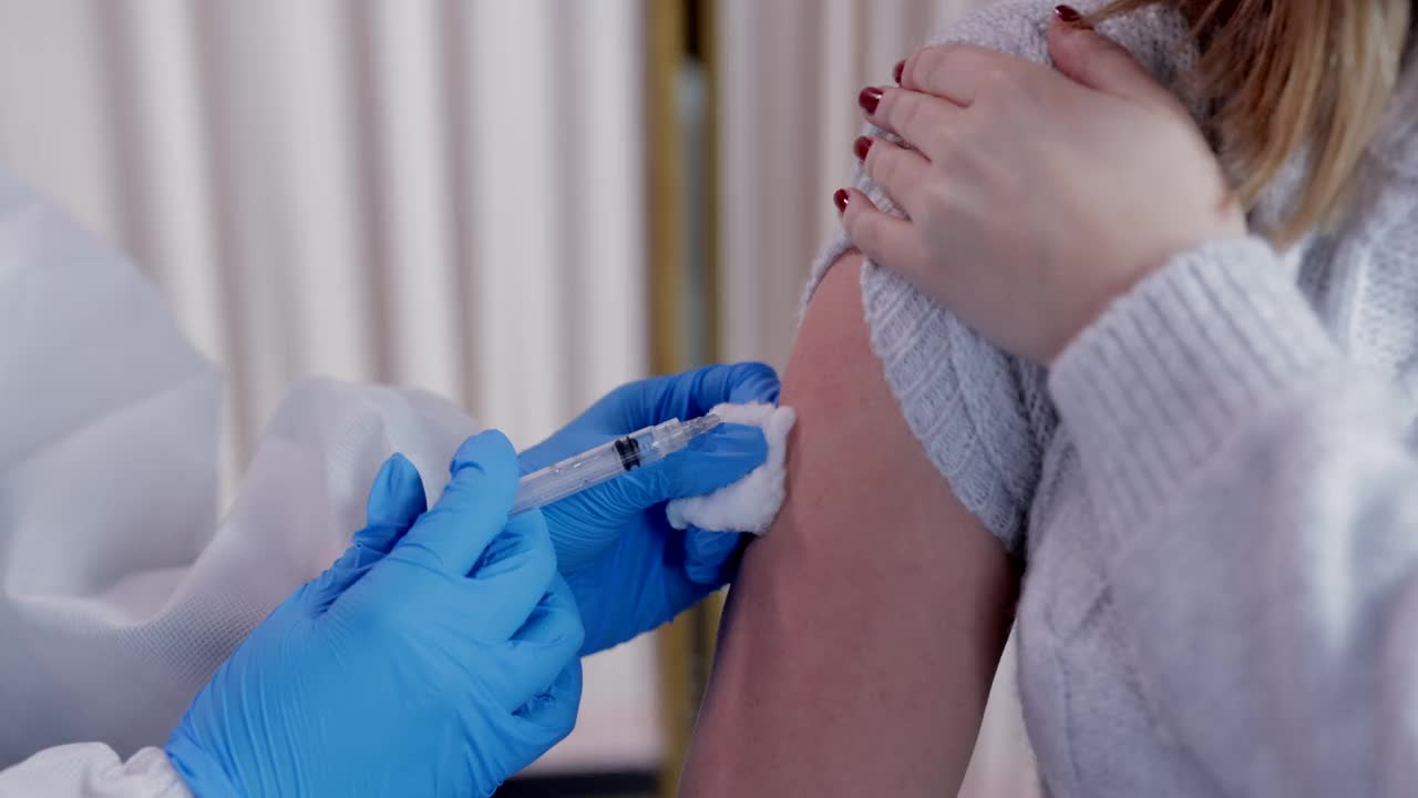 穿着防护服的护士正在给病人的手臂注射疫苗视频素材