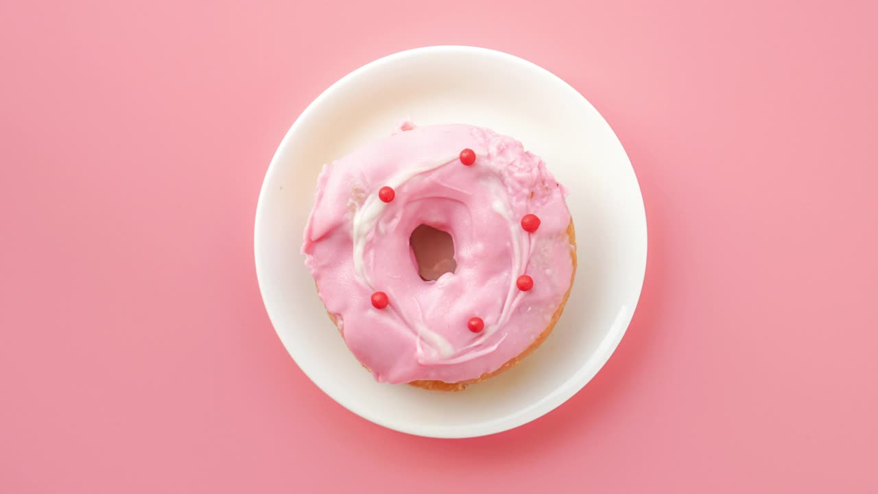 定格动画甜甜圈咬粉红色的背景视频下载