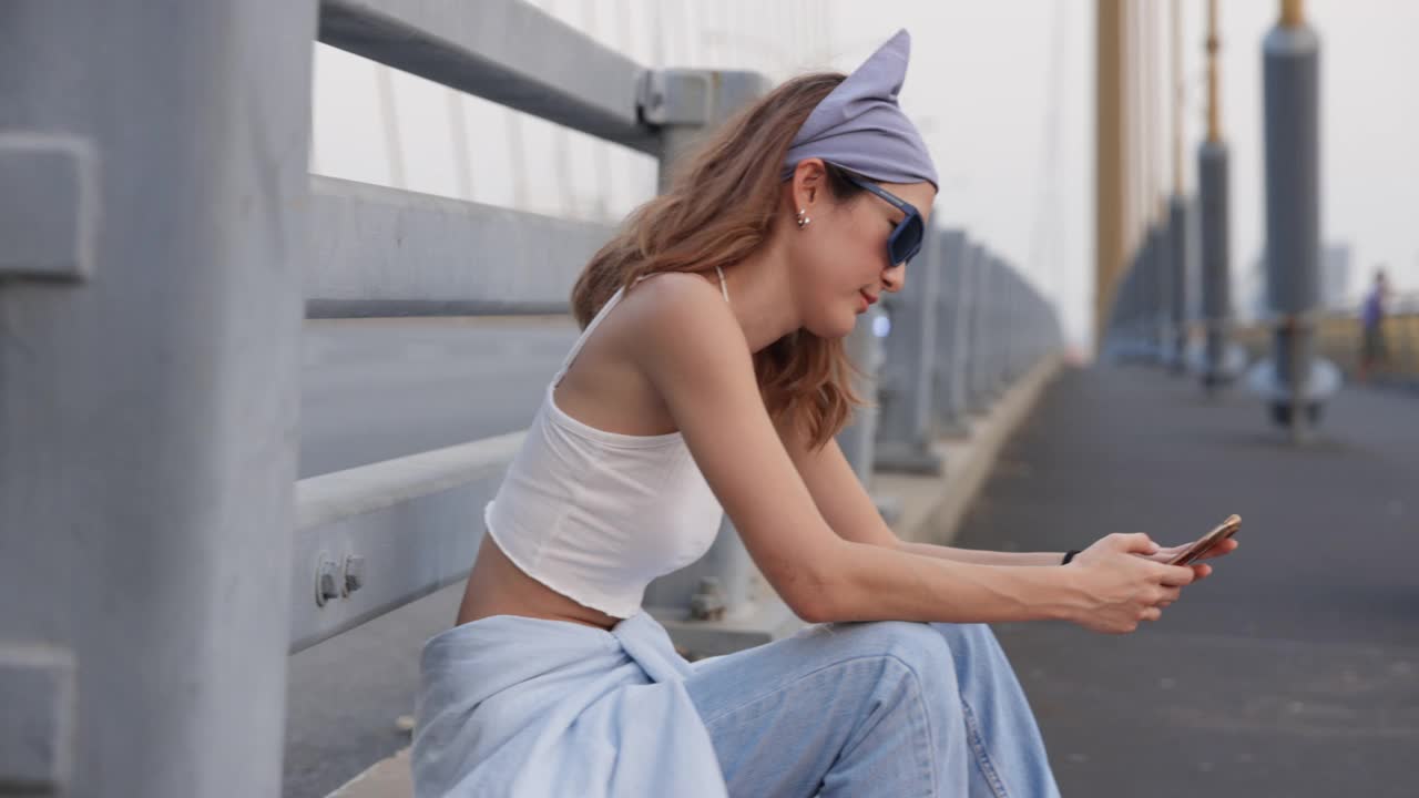 年轻时髦的亚洲女性在街上用手机视频下载