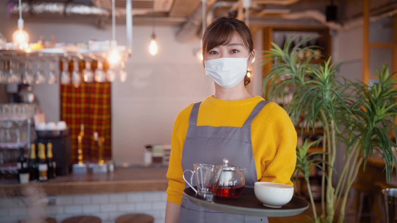 在café上戴着防护面罩的快乐女服务员的画像视频素材