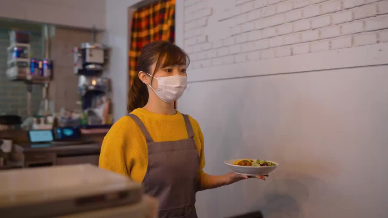戴着防护面罩的服务员在café为顾客提供食物视频下载