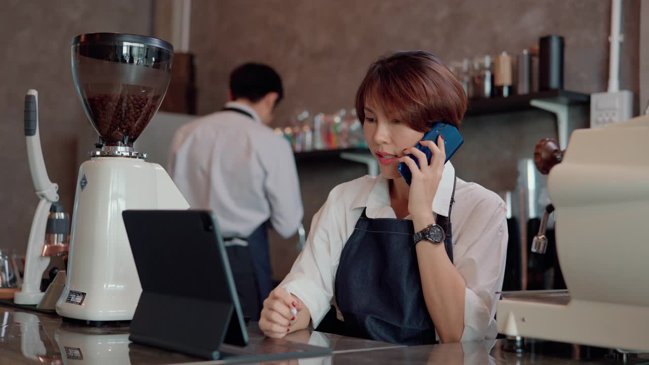 女服务员用智能手机与顾客交谈。视频素材