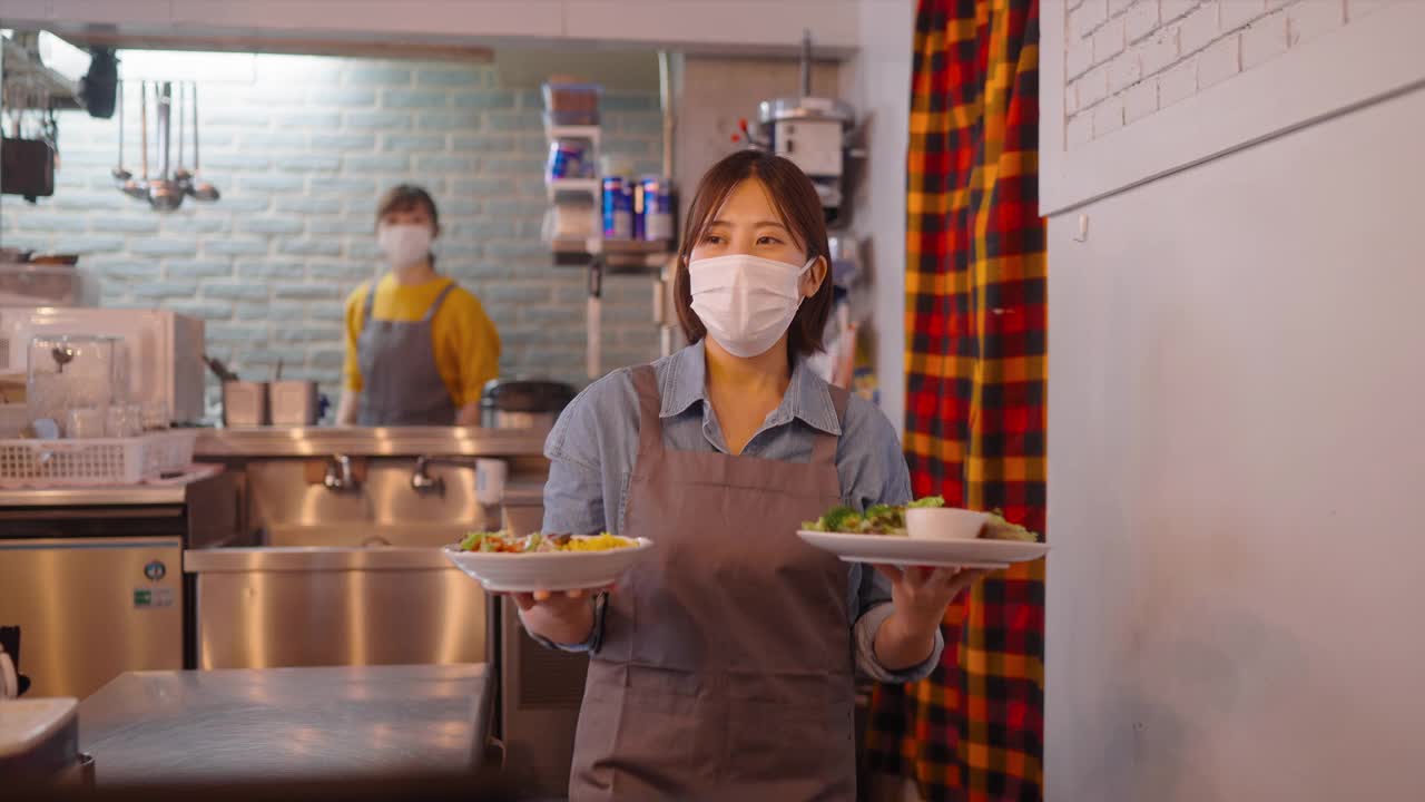 戴着防护面罩的服务员在café为顾客提供食物视频素材