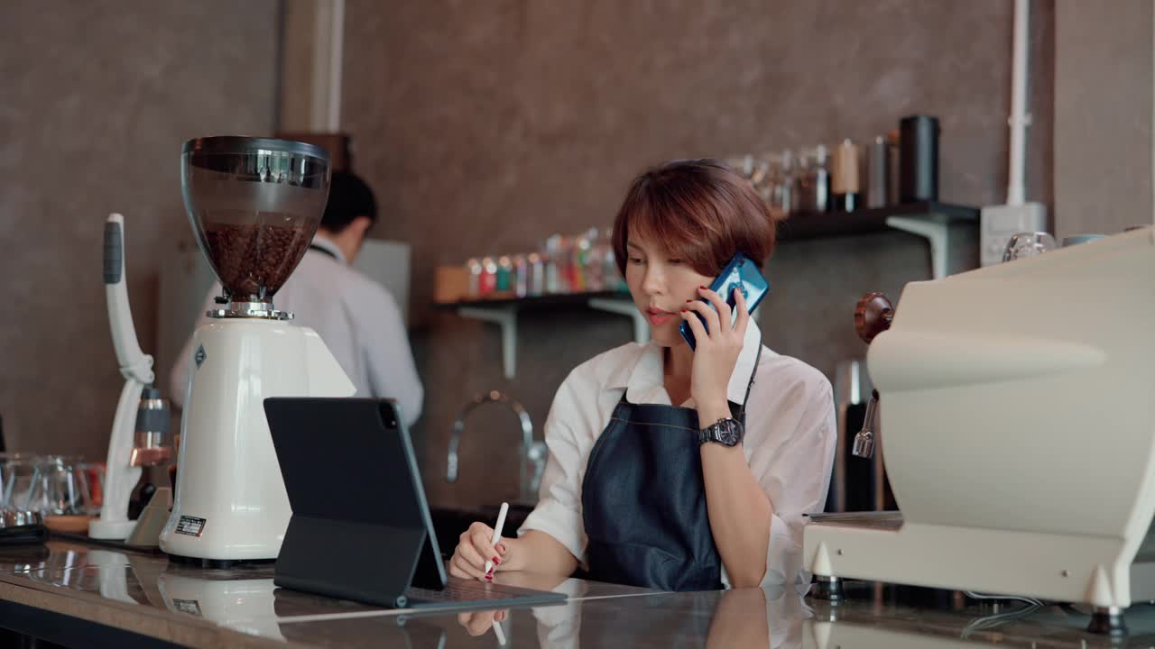 女服务员用智能手机与顾客交谈。视频素材