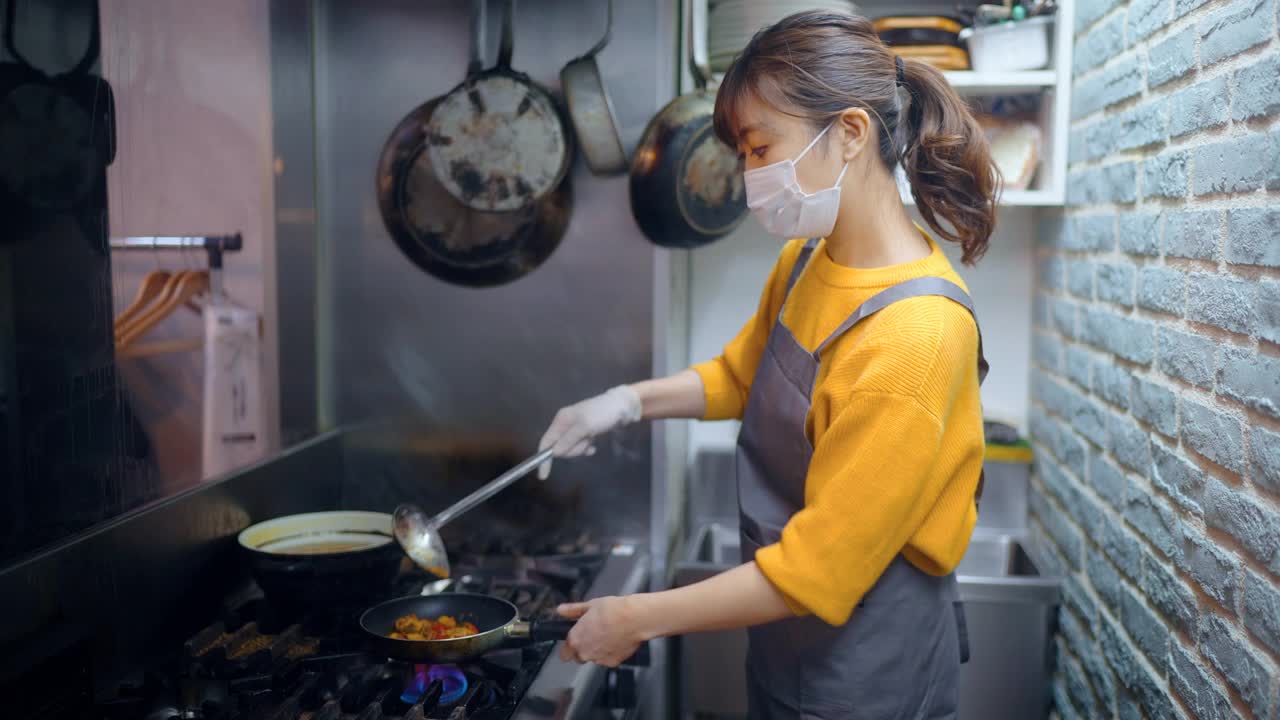 带防护口罩的女厨师在café和餐厅的商业厨房准备食物视频下载