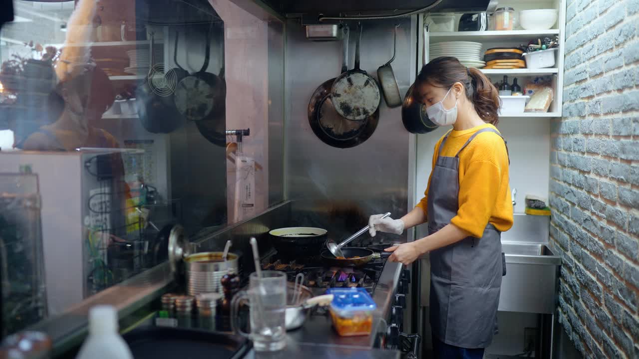带防护口罩的女厨师在café和餐厅的商业厨房准备食物视频下载