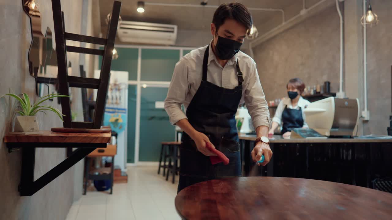 一对夫妇的老板戴着外科口罩在一个封闭的咖啡馆里。视频素材