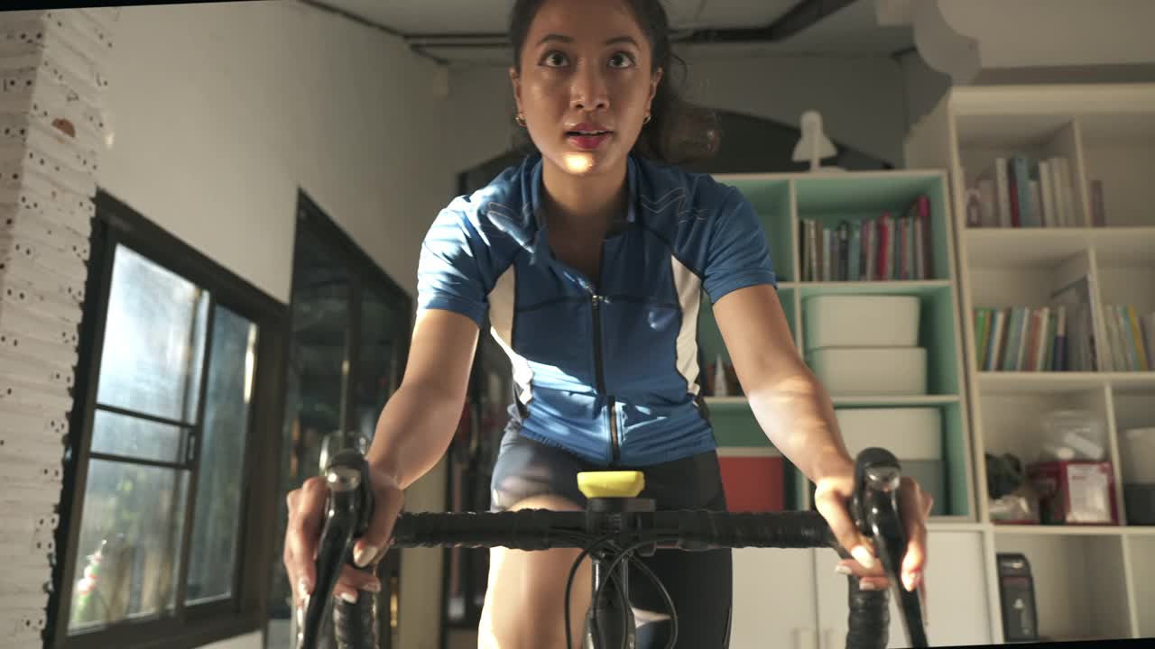亚洲女人骑自行车。她在家锻炼。她在虚拟世界里玩游戏。视频购买