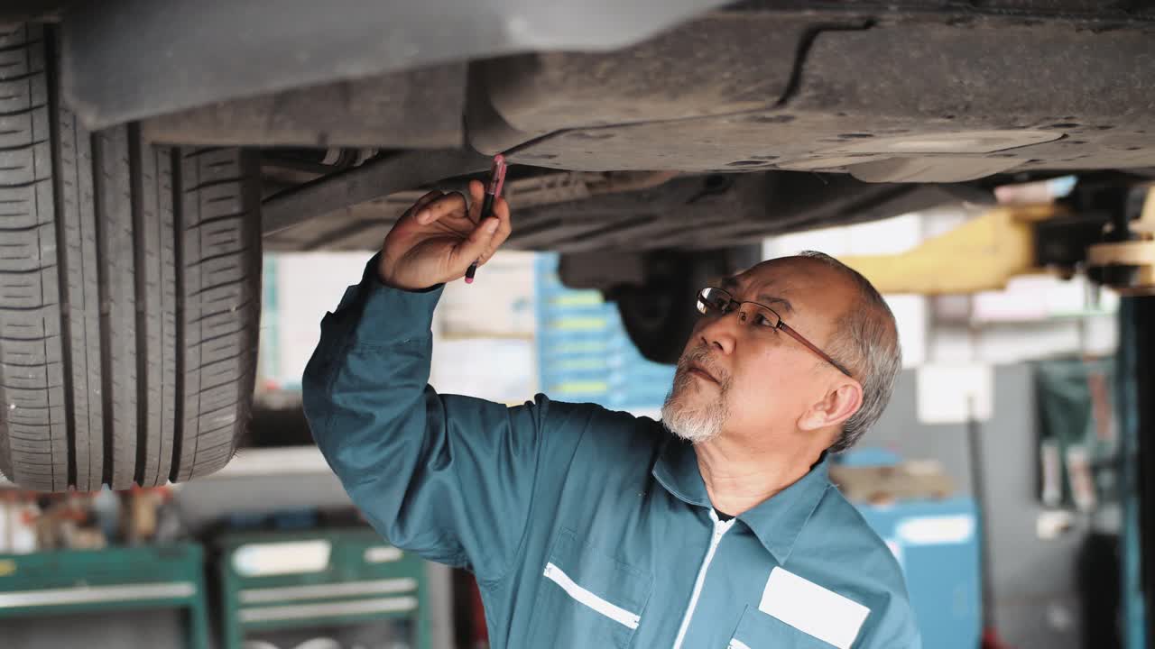 一个成熟的机械师在汽车服务上工作的车辆的肖像镜头视频素材