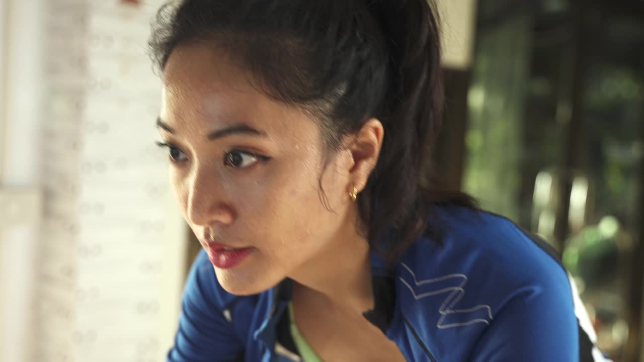 亚洲女人骑自行车。她在家锻炼。她在虚拟世界里玩游戏。视频素材
