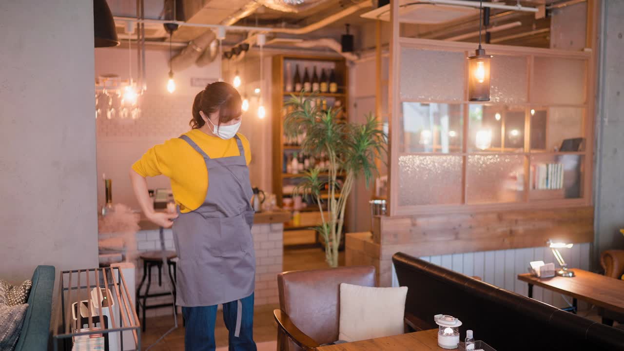 女餐厅老板café戴着防护口罩戴着围裙，准备重新开业她的café视频素材