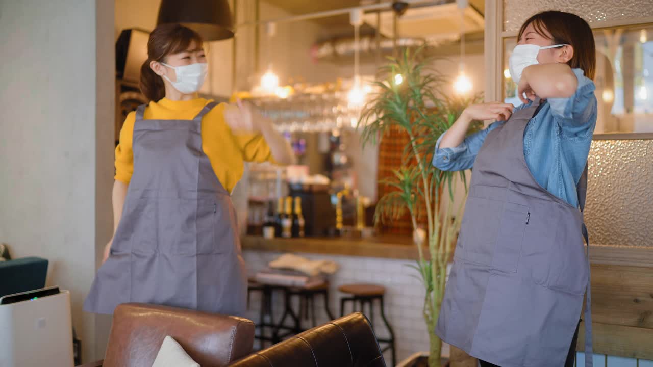 两名戴着防护口罩的妇女在café工作，穿上围裙，准备重新打开café视频下载