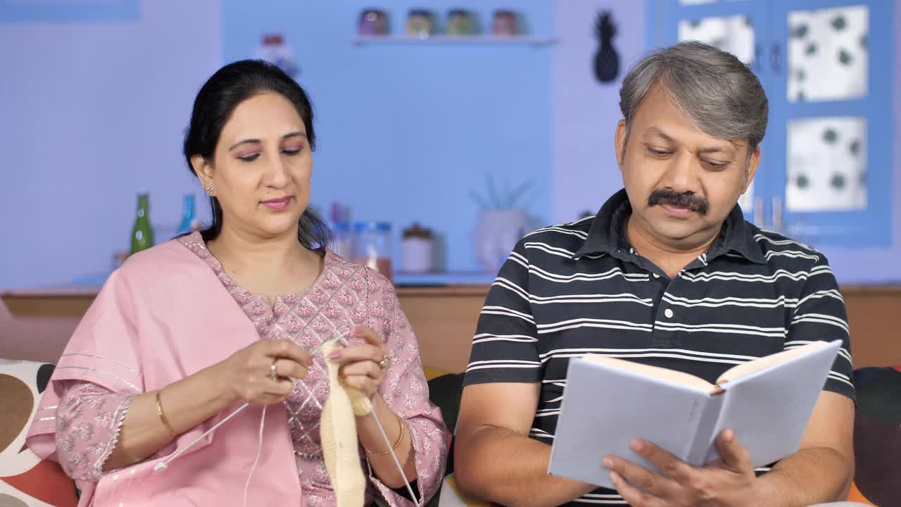 印度男性与灰色头发显示有趣的东西给妻子，而阅读的故事书视频素材