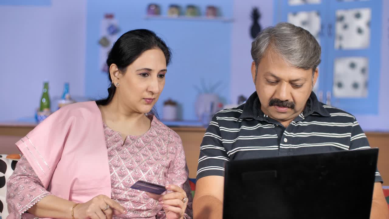 迷人的印度家庭主妇帮助她的丈夫把借记卡/信用卡的详细信息-网上购买视频素材