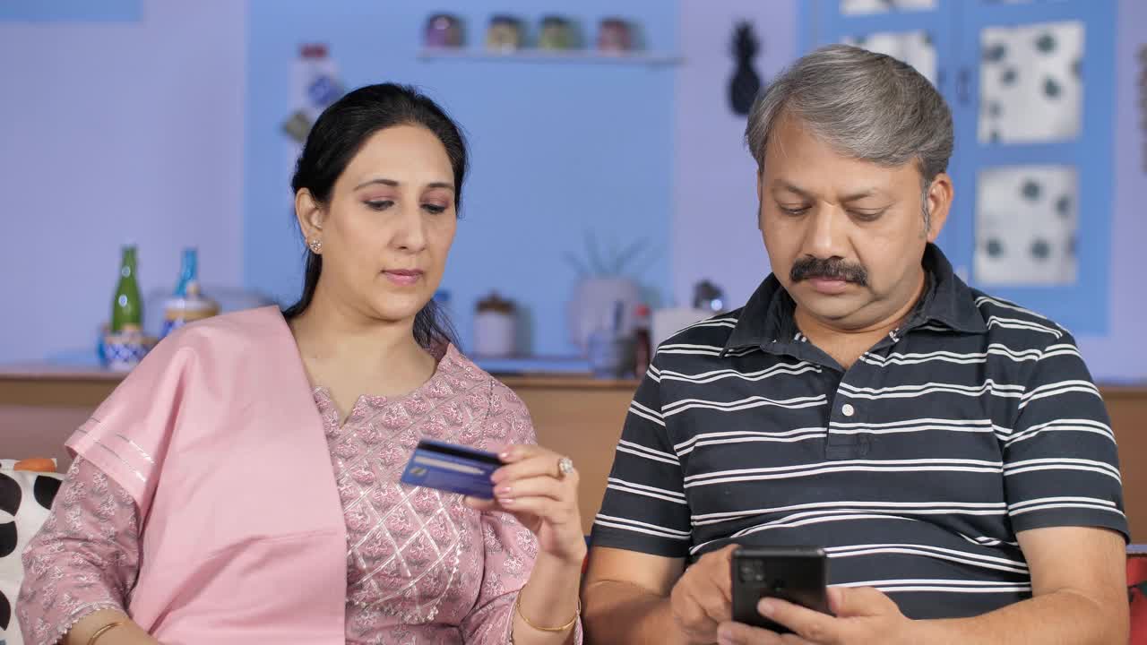 迷人的家庭主妇帮助她的丈夫把信用卡/借记卡的详细信息在网上航运视频素材