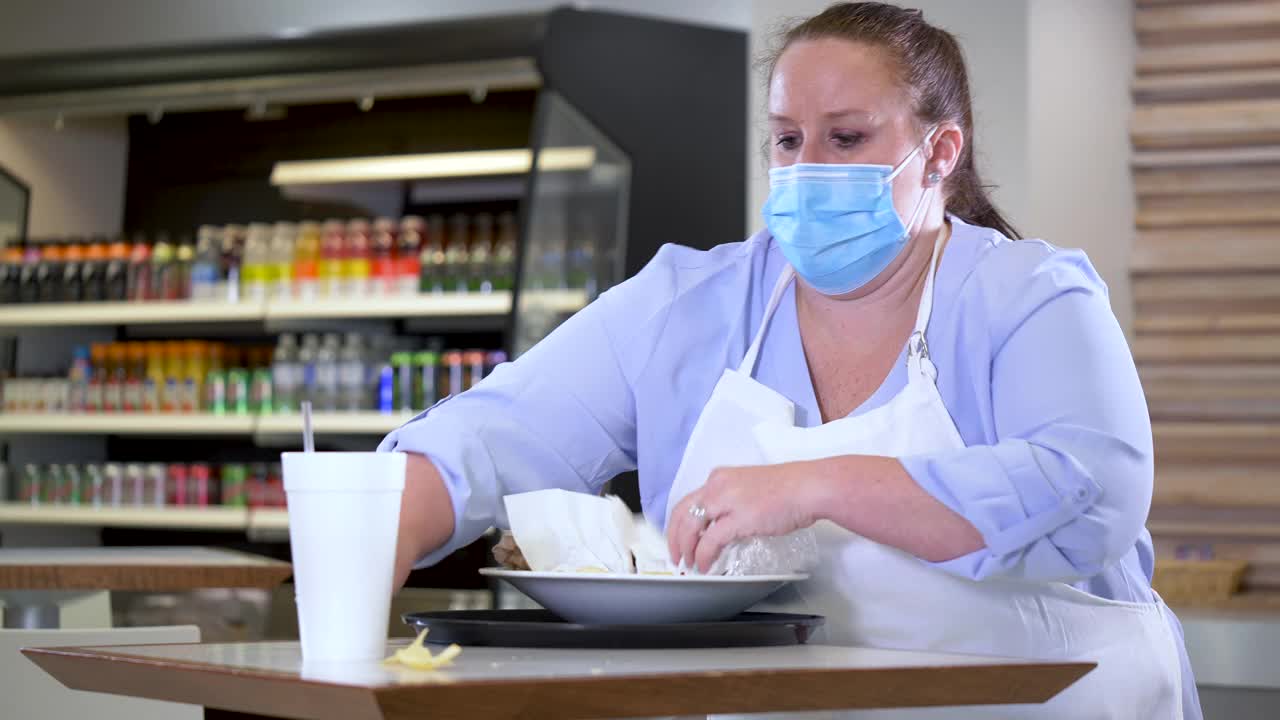 餐厅的女服务员戴着面具在清理桌子视频素材