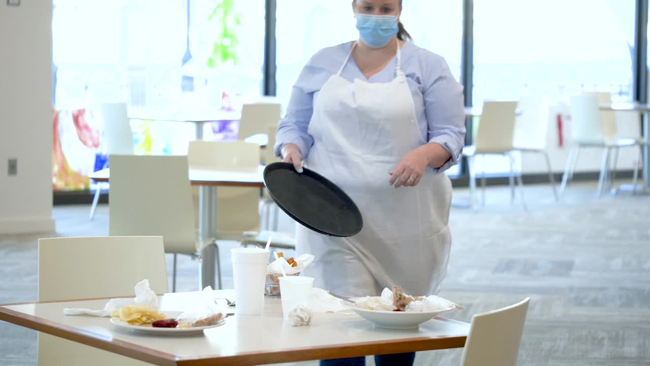 餐厅里的女服务员在擦桌子，戴着口罩视频素材