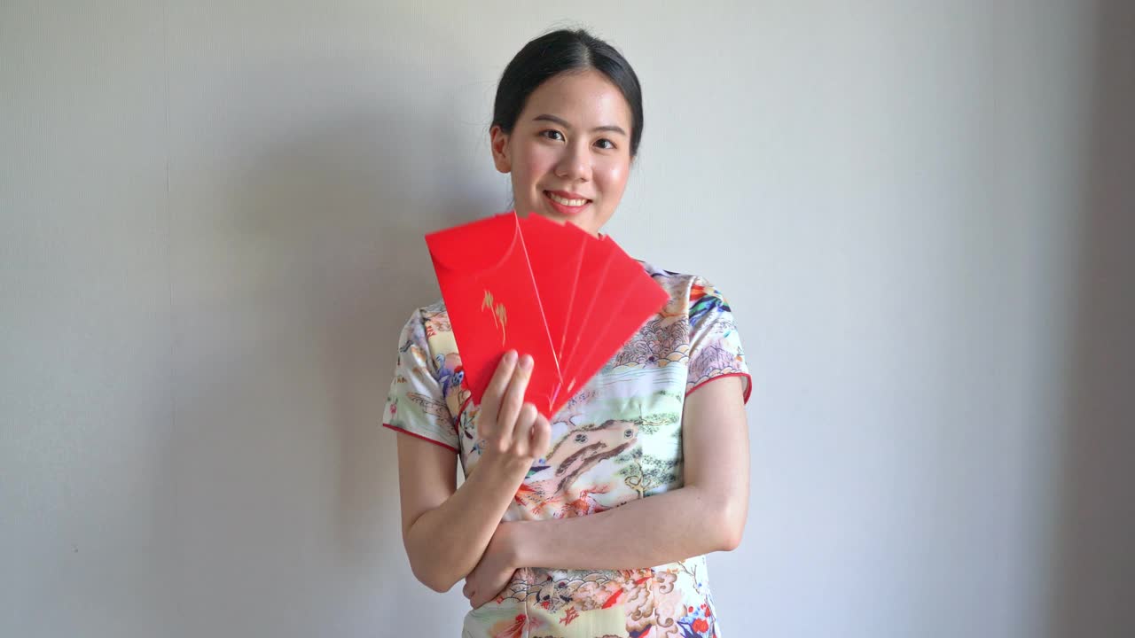 美丽的亚洲妇女穿着带有红包的中国传统服装视频下载
