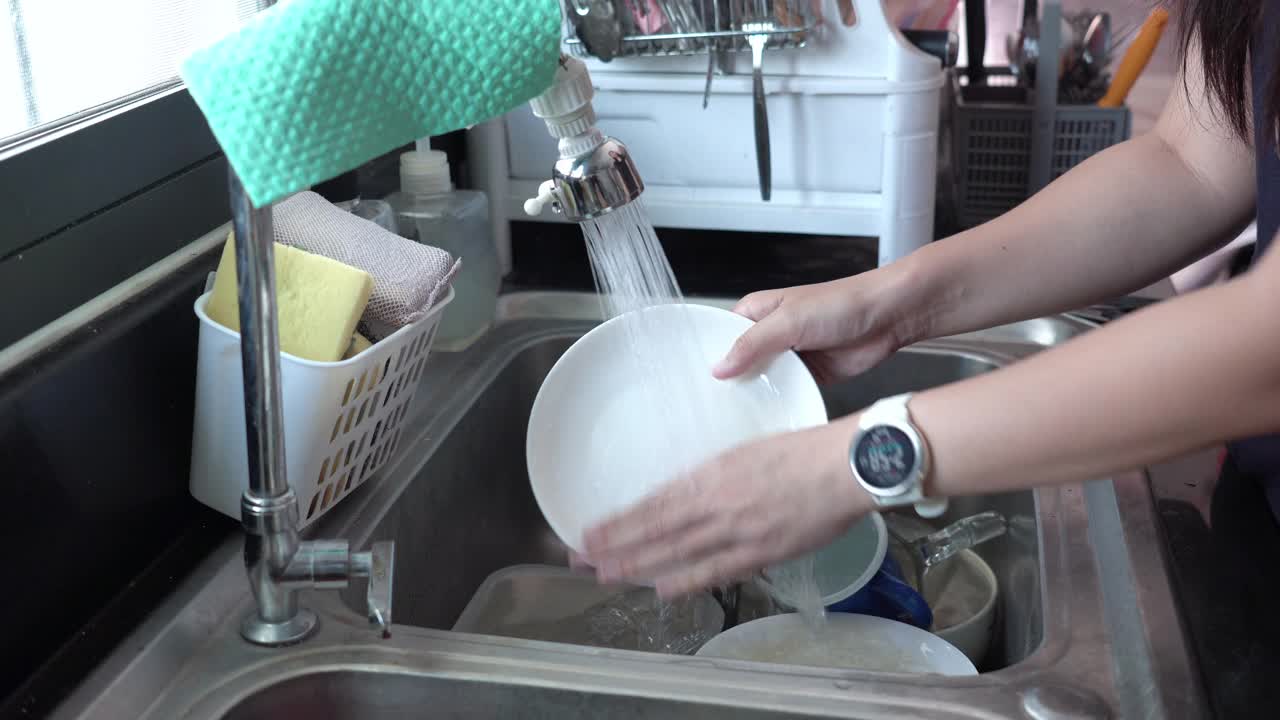 在厨房水槽里洗盘子的女人。视频下载