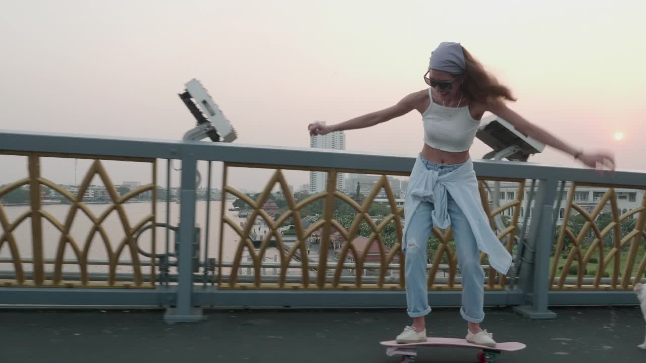 年轻时髦的亚洲女人在晚上的桥上玩滑板视频素材
