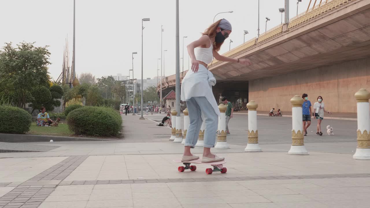 年轻时髦的亚洲女人在桥下的公园玩滑板视频素材