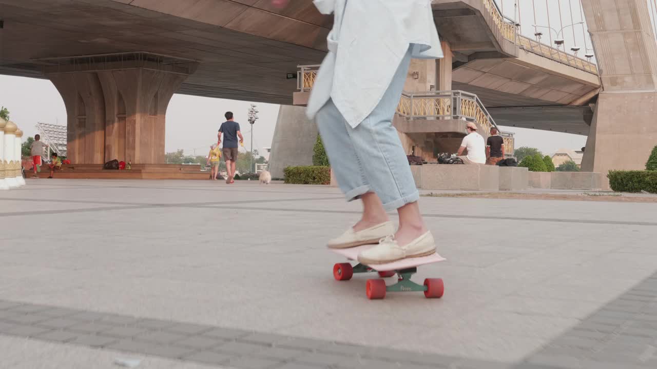 年轻时髦的亚洲女人在桥下的公园玩滑板视频下载