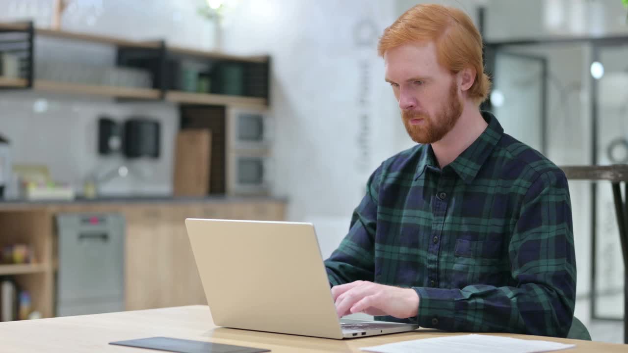 年轻的红发胡子男人用笔记本电脑显示拇指向下视频素材