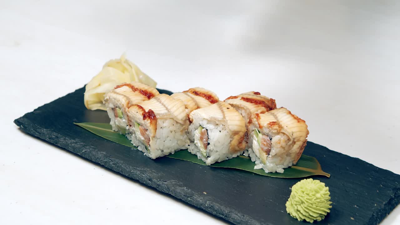 特写的美味寿司卷与烟熏鳗鱼在盘子上。在餐馆里做寿司卷。副本的空间。视频素材