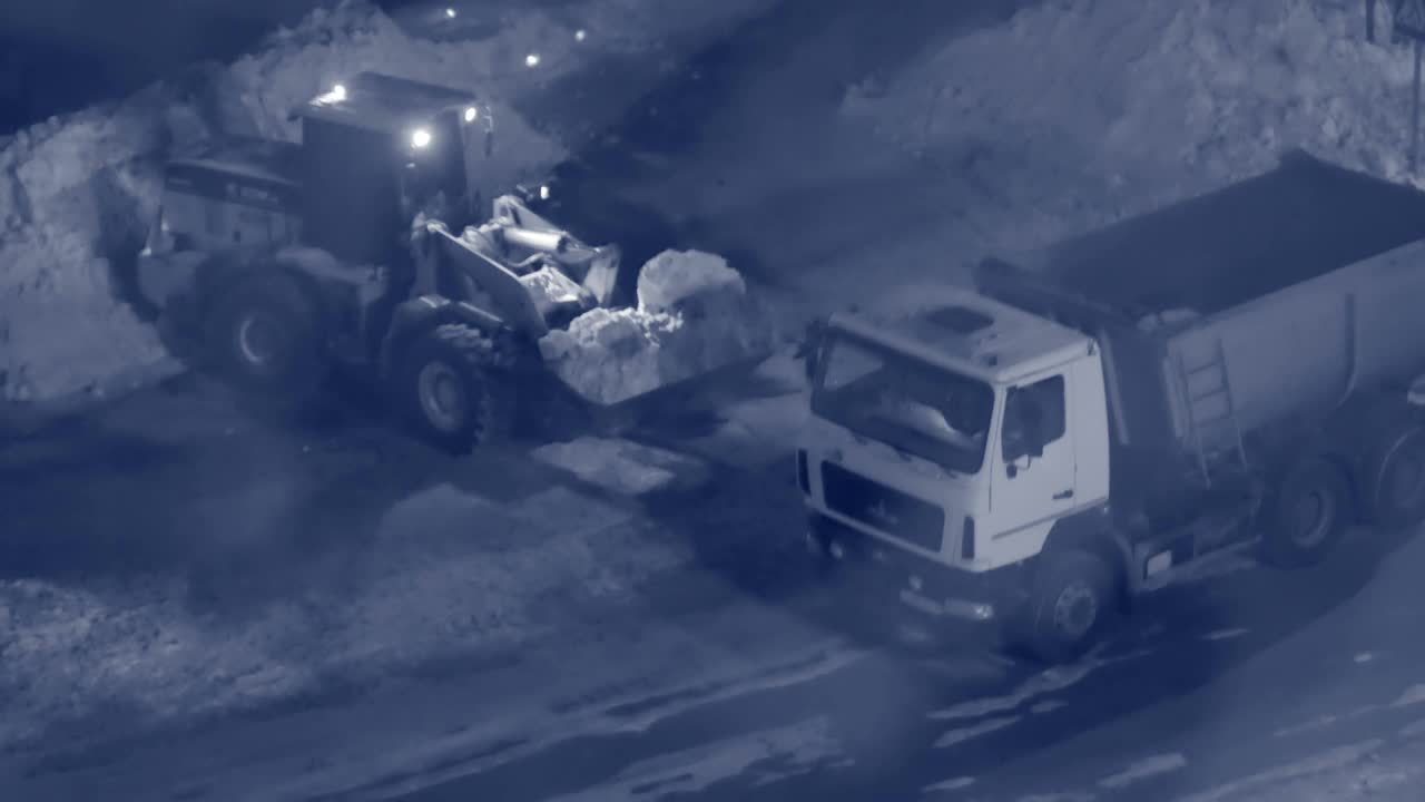 一辆大型拖拉机清除城市道路上的积雪。在一辆大卡车上折叠雪。晚上的时间视频素材