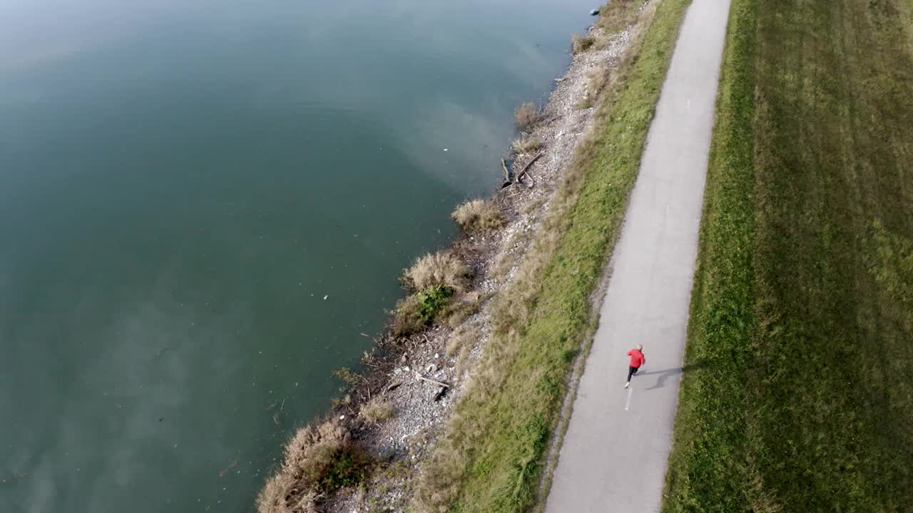 4K无人机从远处拍摄了一个人在湖边奔跑的画面视频素材