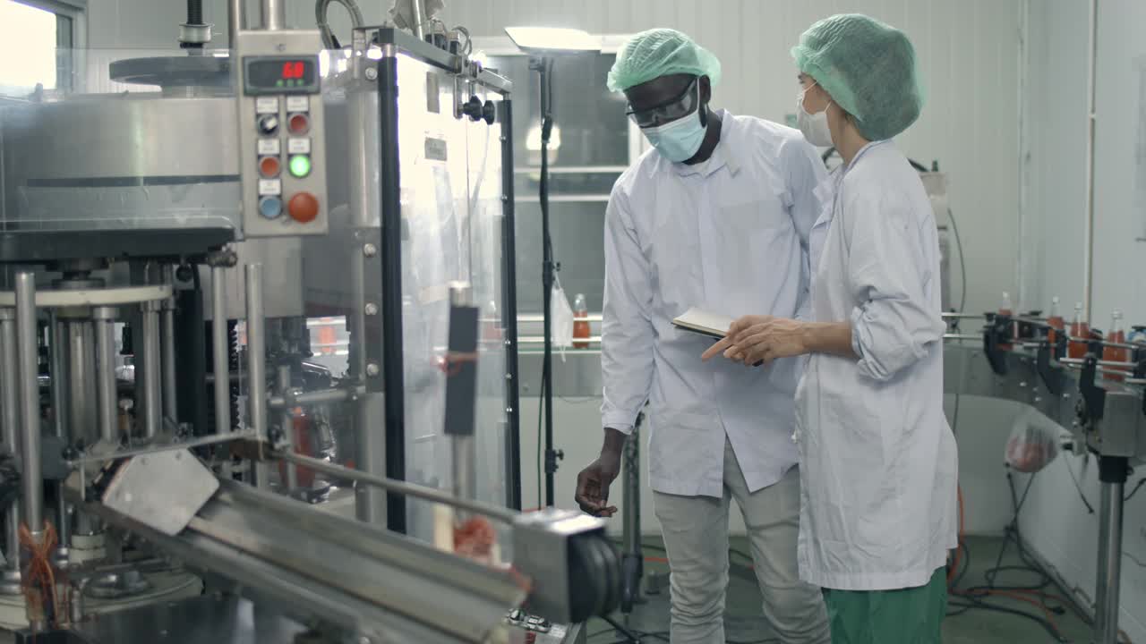 两名工厂工人穿着防护服控制着输送带上产品的质量视频素材