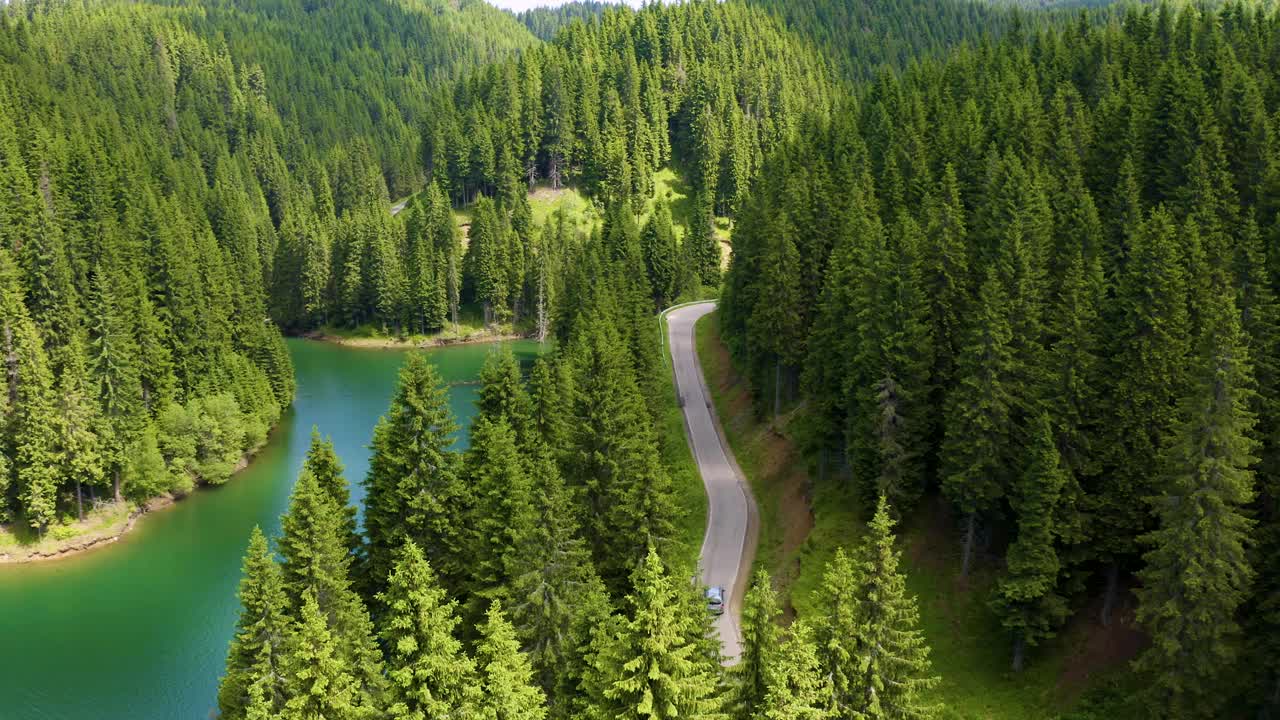 鸟瞰图的汽车驾驶通过前和湖的一边。美丽的山路。在山路上开车。公路旅行。山地森林湖泊景观。汽车穿过松林视频素材