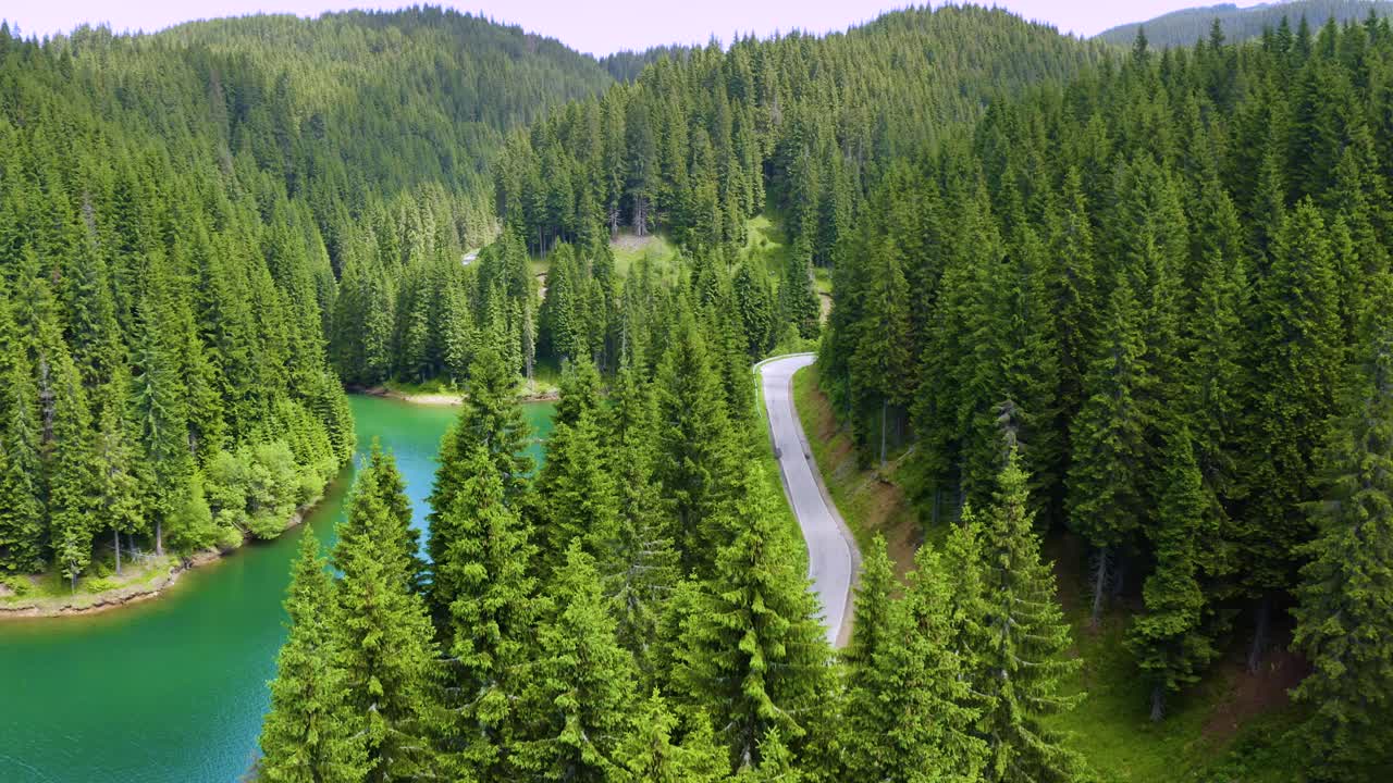 鸟瞰图的汽车驾驶通过前和湖的一边。美丽的山路。在山路上开车。公路旅行。山地森林湖泊景观。汽车穿过松林视频素材