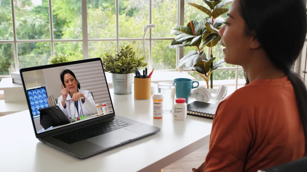亚洲妇女病人与她的医生视频通话，在家里使用药片要求处方，病人有一个远程顾问关于她的疾病。视频素材