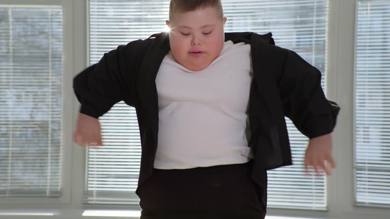 生活与残疾，胖胖的男孩与唐氏综合症有乐趣和蹦床上跳窗户特写背景视频下载