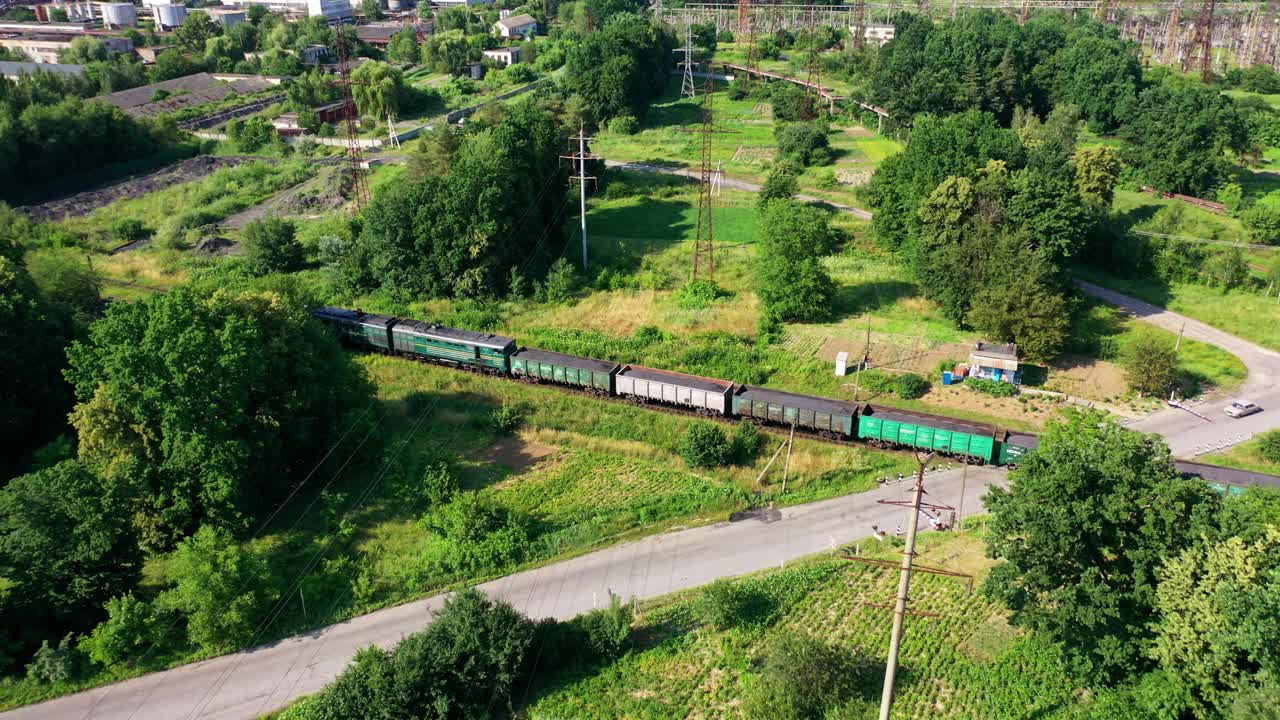 在铁路上行驶的货运列车。夏季，货运列车在绿色的大自然中穿梭。鸟瞰图。视频素材