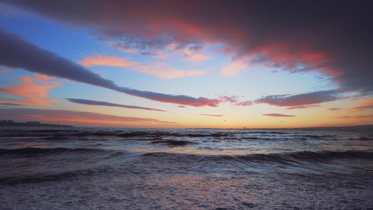 海上戏剧性的日落。美丽的红色和蓝色的云在海洋日落表面和海鸟或海鸥飞在水上视频素材